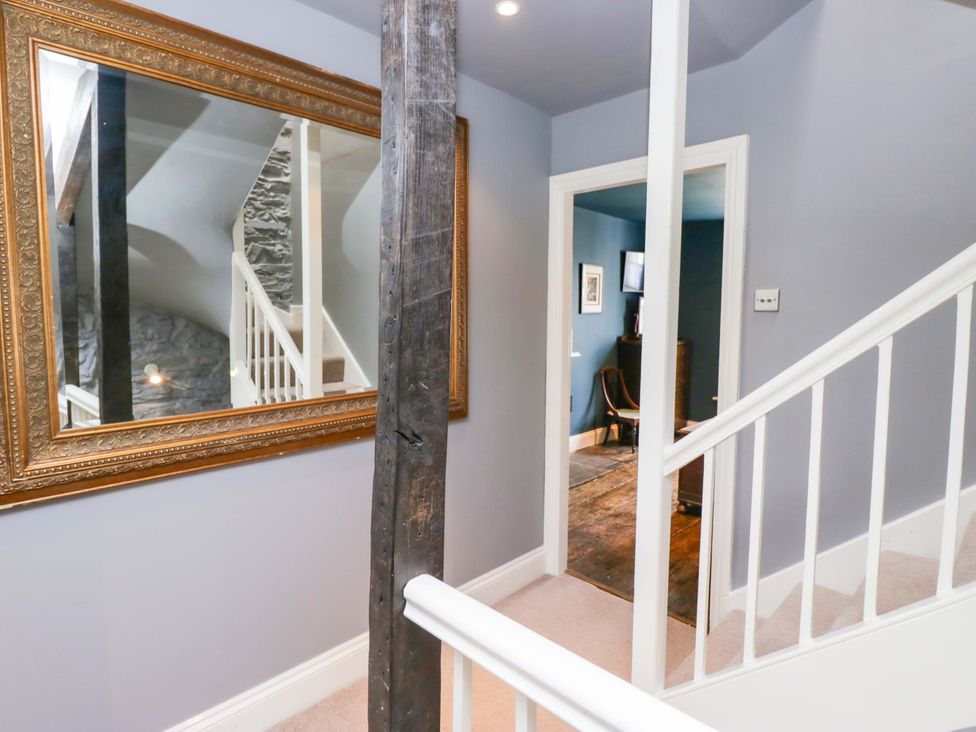 A hallway with a mirror and staircase at Unicorn Cottage