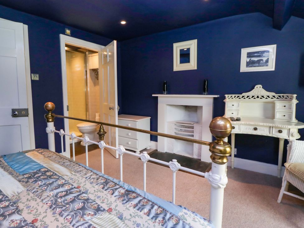 A bedroom with a bed and a bathroom door at Unicorn Cottage