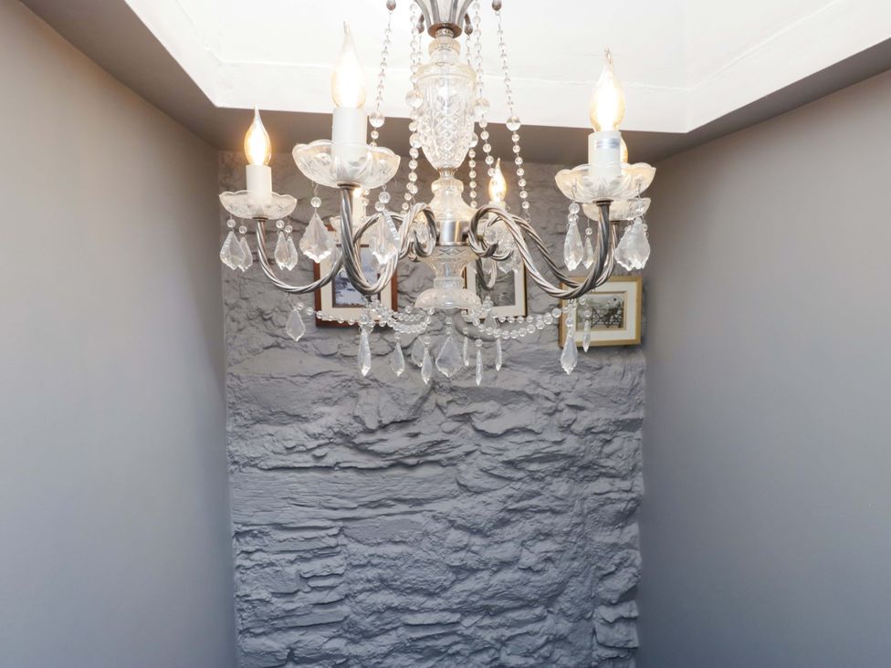 A chandelier with wall pictures in a hallway at Unicorn Cottage