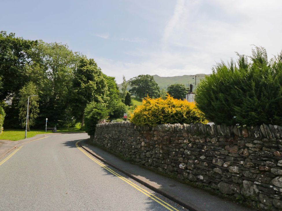 A road with stone wall and trees at Unicorn Cottage in 