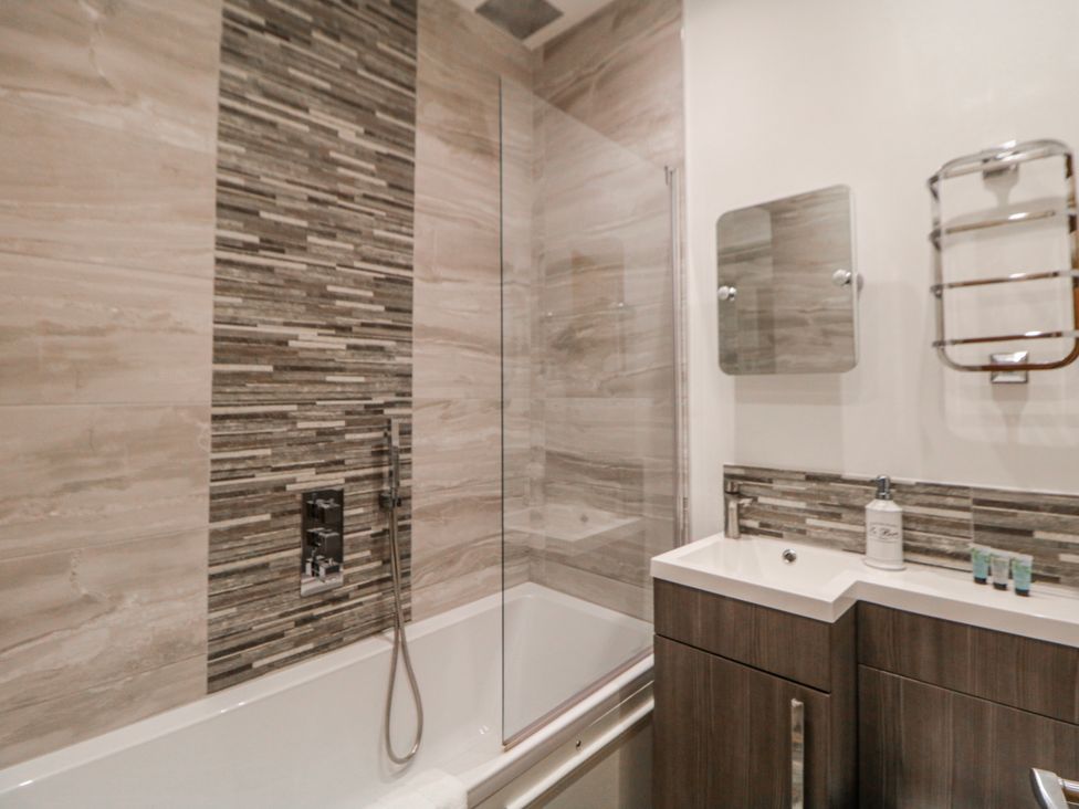 A bathroom with a bathtub, shower, and sink at Masson (78) in Matlock