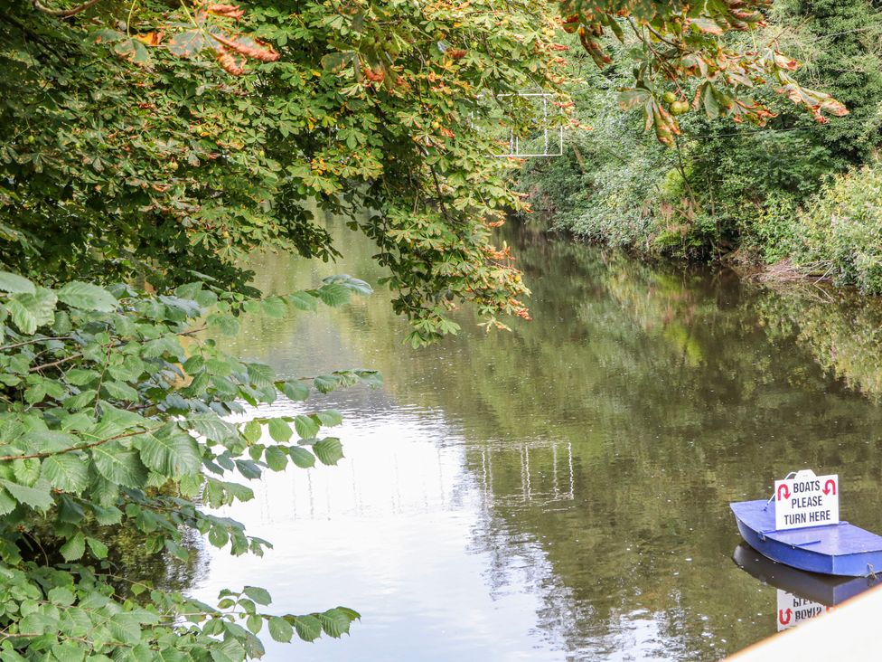 A river with a boat and a sign at Masson (78) Matlock