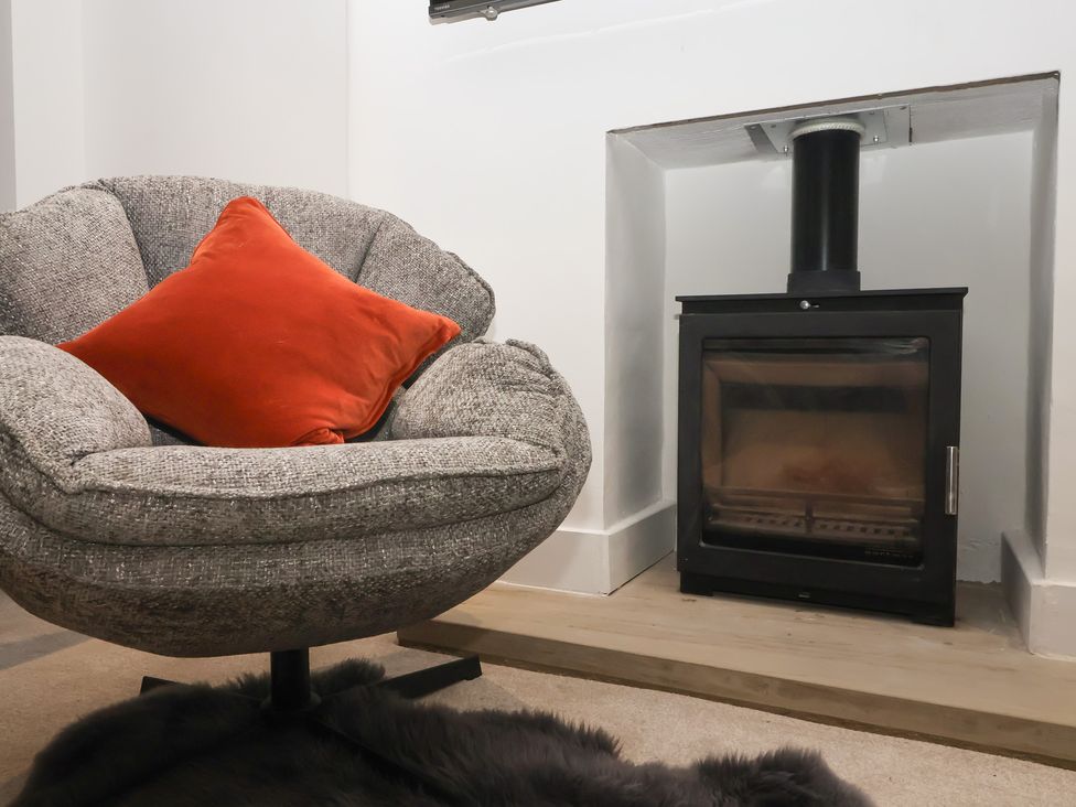A living room with a chair and stove at Virginia Cottage in Skipton