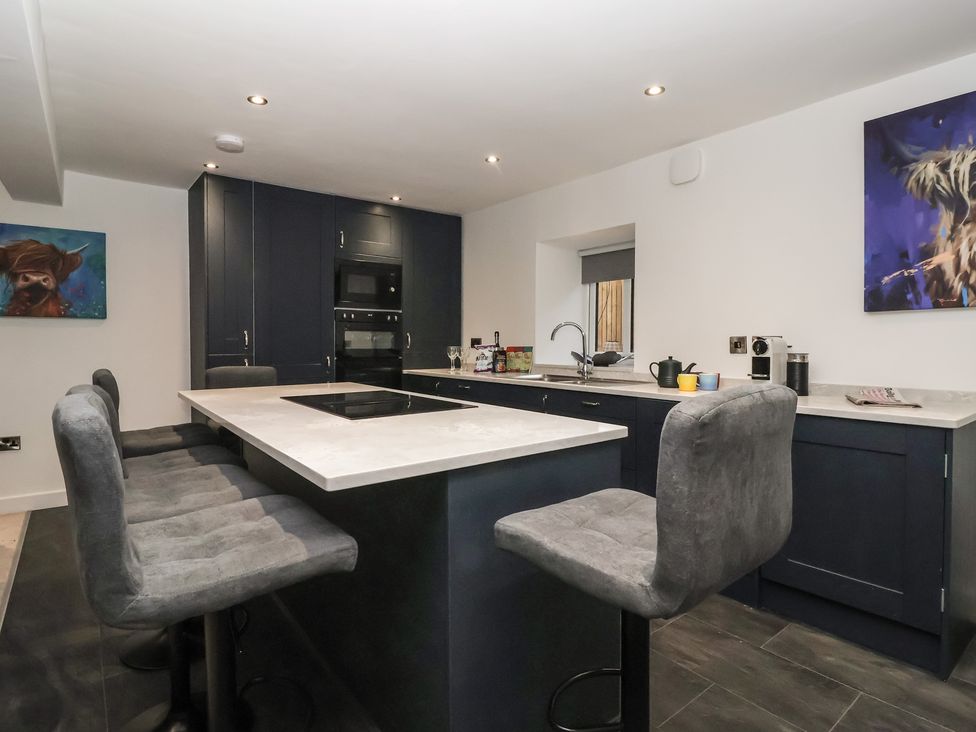A kitchen with an island and stools at Virginia Cottage in Skipton