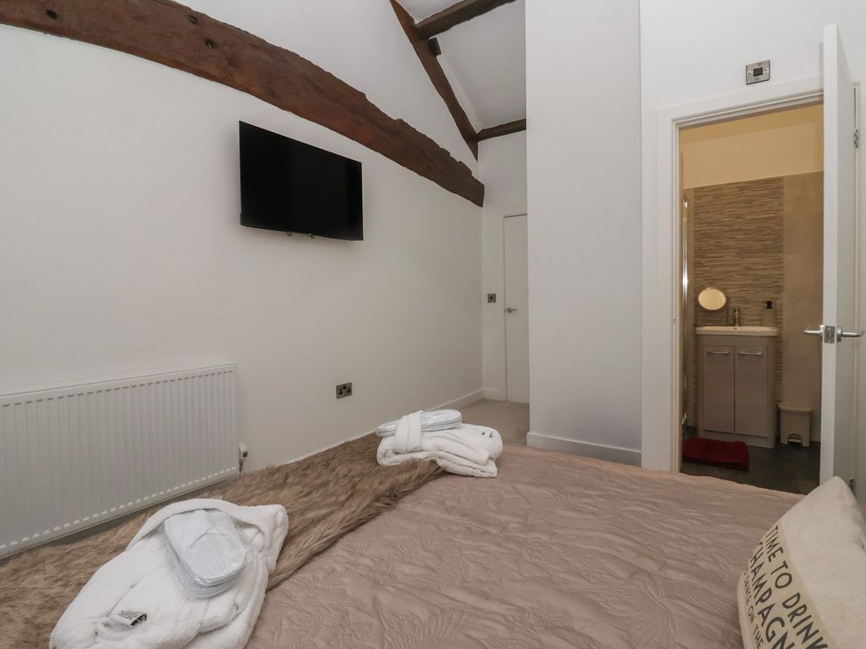 A bedroom with a television and a door leading to a bathroom at Virginia Cottage Skipton