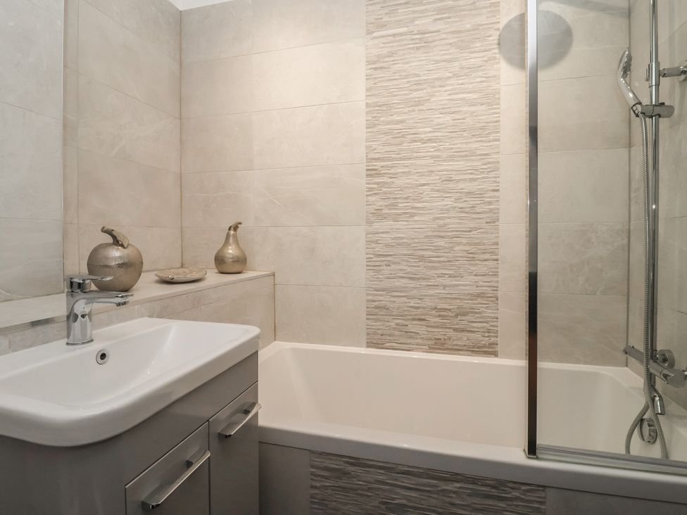 A bathroom with a bathtub, shower, and sink at Virginia Cottage in Skipton