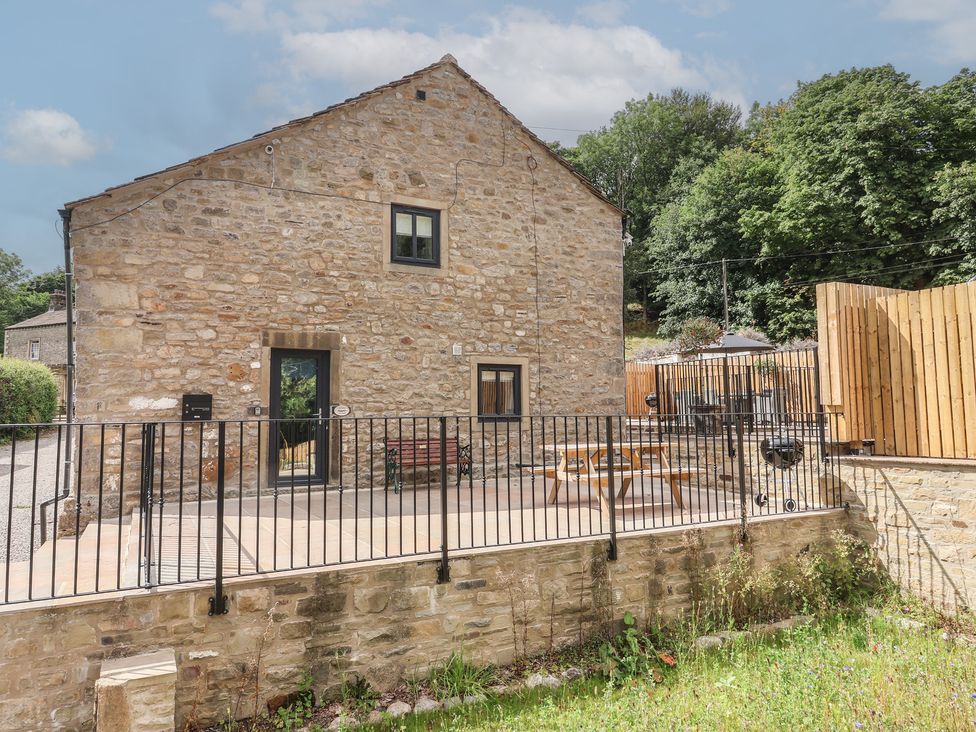 A stone house with a fenced patio and outdoor furniture at Virginia Cottage Winterburn