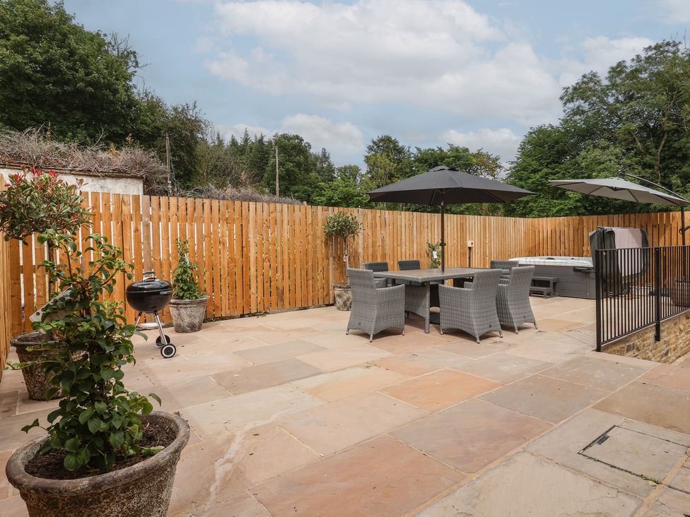 An outdoor patio with furniture and a hot tub at Virginia Cottage in Winterburn