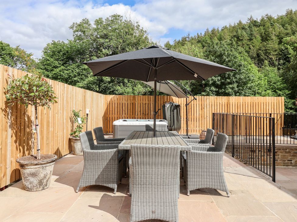 A garden with a table and chairs under an umbrella at Virginia Cottage Winterburn
