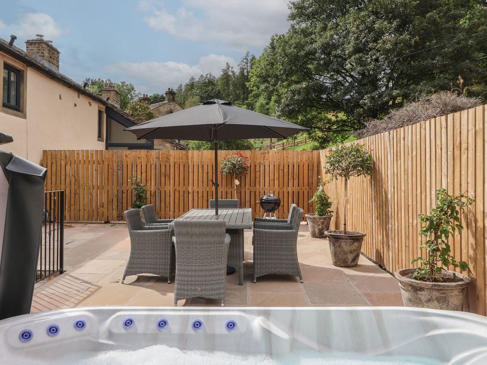 An outdoor area with a hot tub, table, and chairs at Virginia Cottage in Winterburn