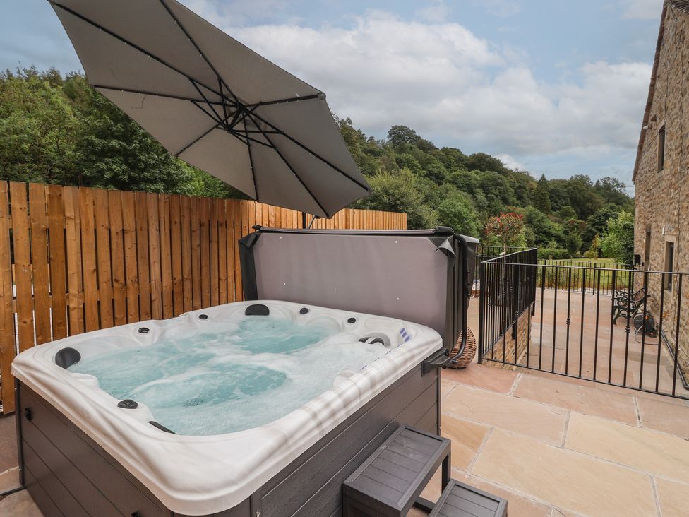 A hot tub with an umbrella in an outdoor area at Virginia Cottage in Winterburn