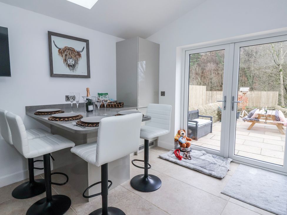 A kitchen with a table and bar stools at Beckside in Skipton