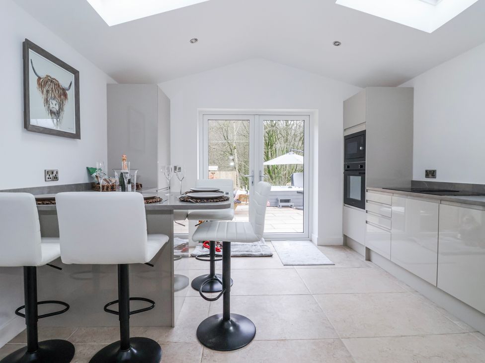 A kitchen with bar stools and a dining table at Beckside in Skipton