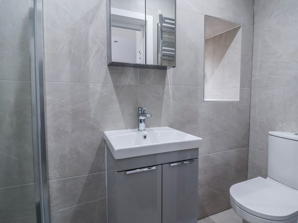 A bathroom with a sink, toilet, and mirror at Beckside in Skipton