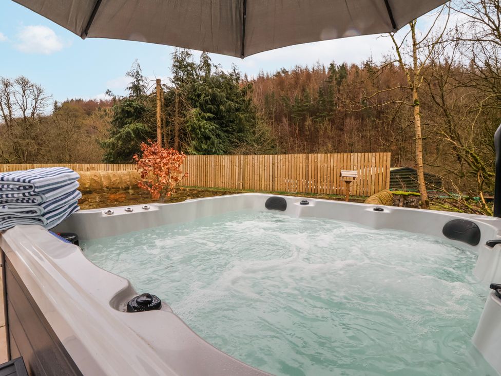 A hot tub with towels and an umbrella in an outdoor area at Beckside in Skipton