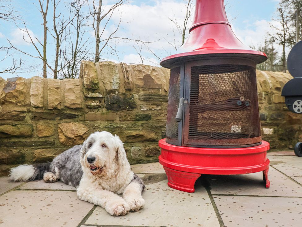 A dog lying next to a red fire pit on a patio at Beckside in Skipton