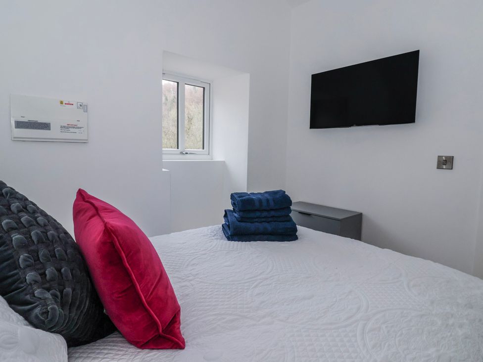 A bedroom with a bed, towels and a television at John's Lodge in Gargrave