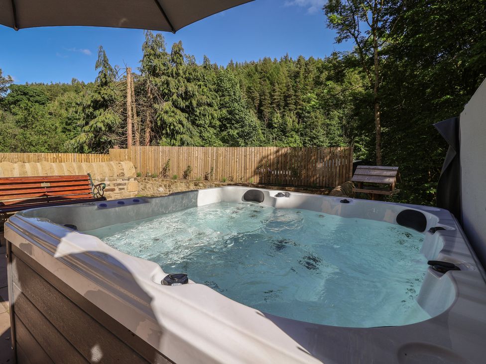 A hot tub with a bench and trees at John's Lodge in Winterburn
