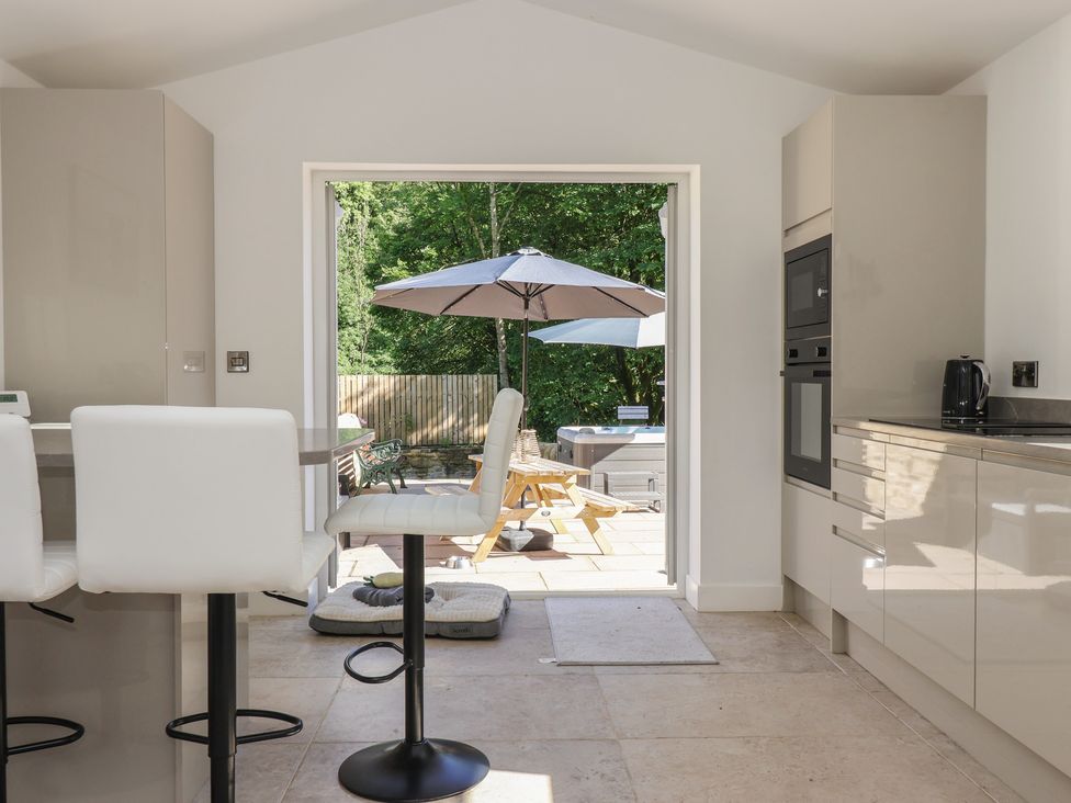 A kitchen with bar stools and a doorway to an outdoor patio at John's Lodge in Winterburn
