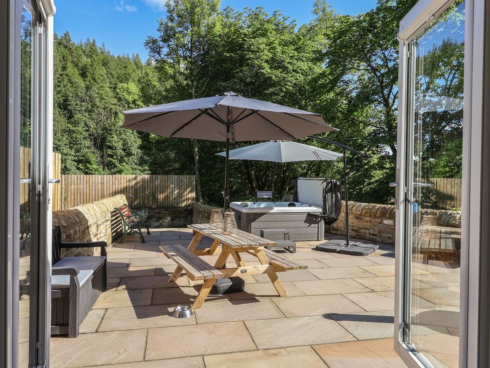 An outdoor patio with a hot tub and seating area at John's Lodge in Winterburn