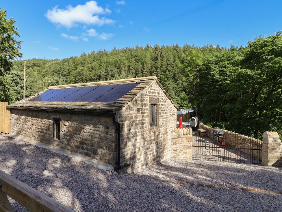 A stone building with solar panels and a gravel driveway at John's Lodge in Winterburn