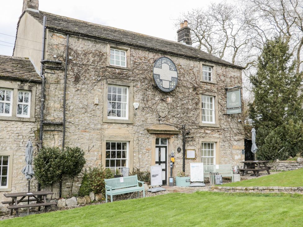 A building with a stone facade and benches outside at John's Lodge in Winterburn