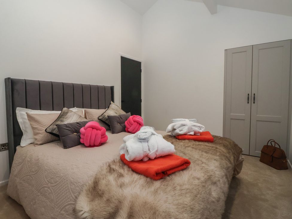 A bedroom with a bed and bathrobes at Wood Cottage in Skipton