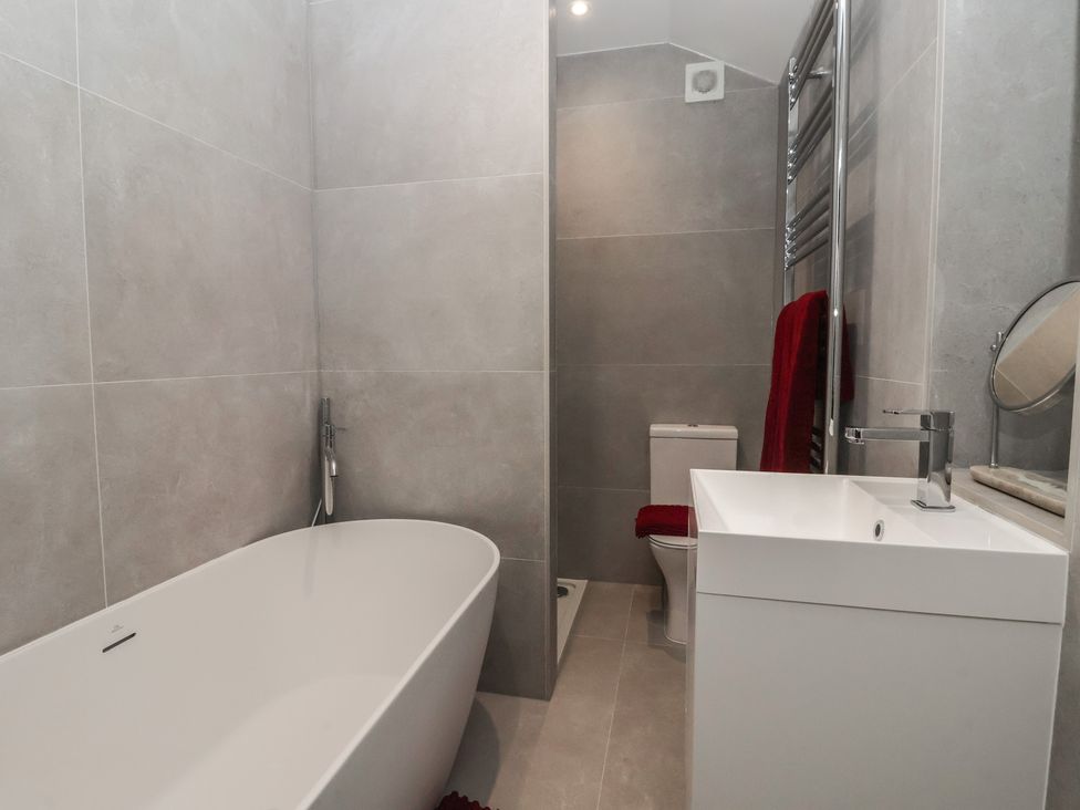 A bathroom with a bathtub, toilet and sink at Wood Cottage in Skipton