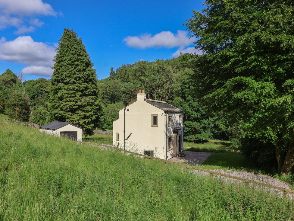 A house with trees and a shed in a grassy area at Wood Cottage in Skipton