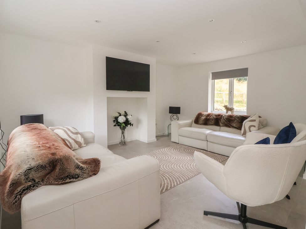 A living room with sofas and a television at Wood Cottage in Winterburn