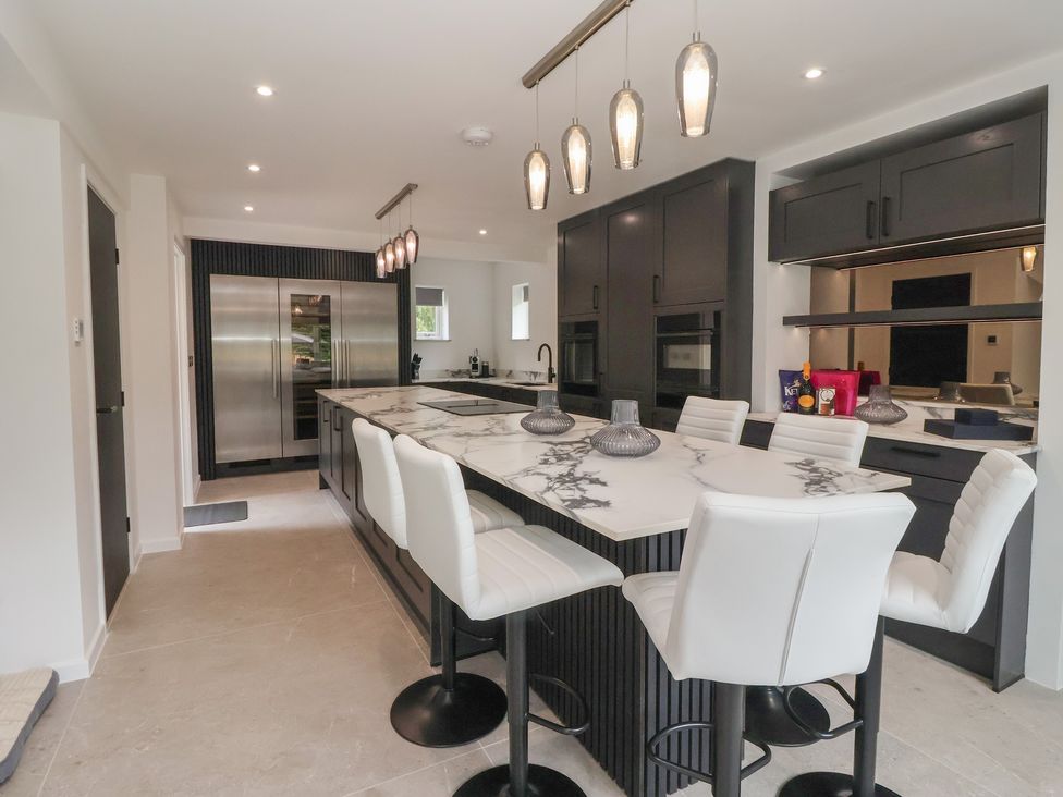 A kitchen with an island and bar stools at Wood Cottage in Winterburn