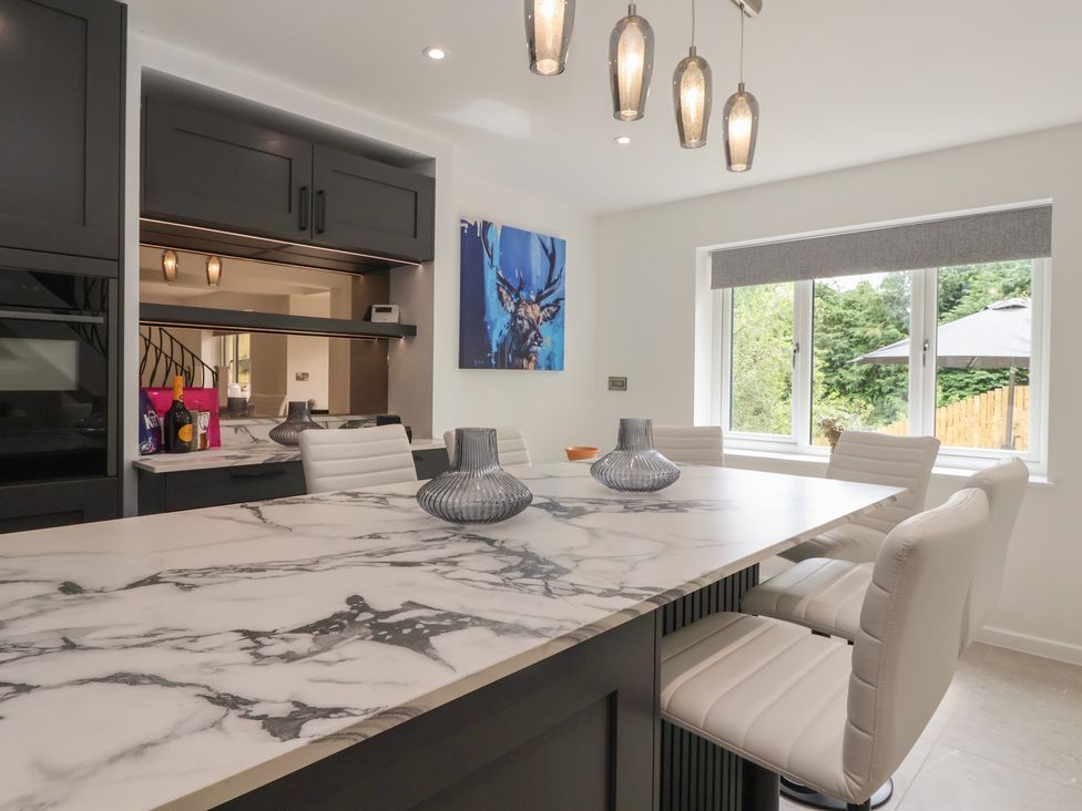 A kitchen with a marble island and bar stools at Wood Cottage in Winterburn
