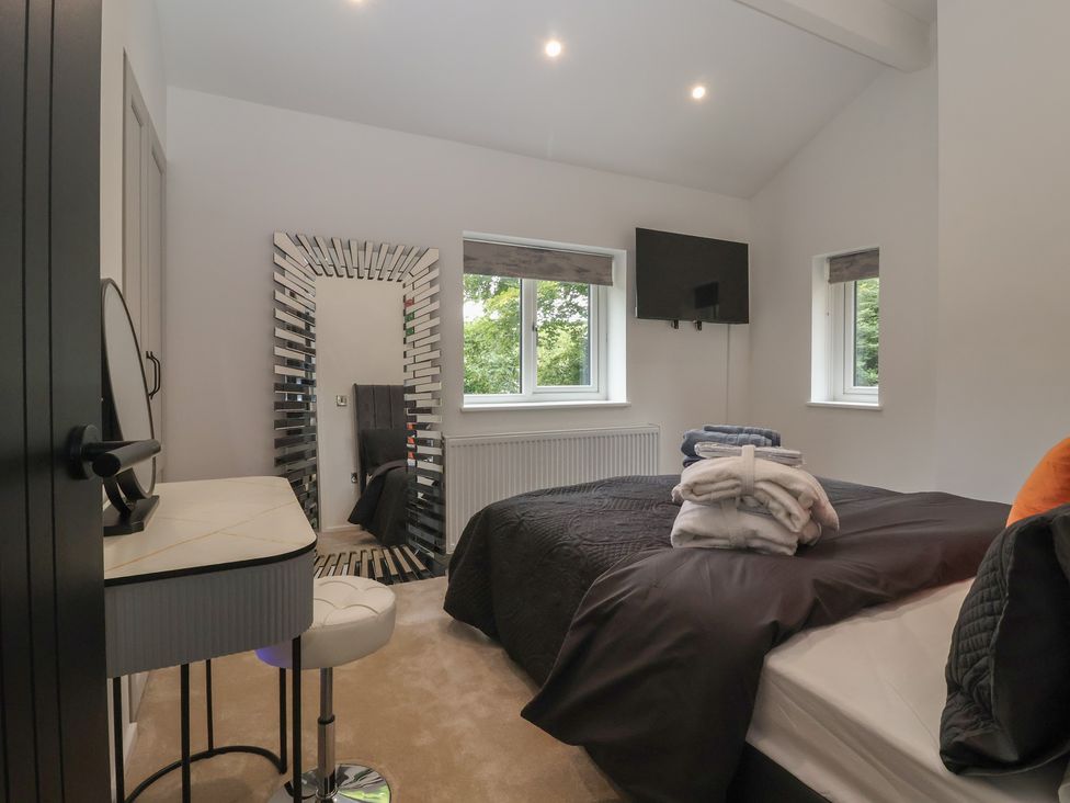 A bedroom with a bed, mirror, and television at Wood Cottage in Winterburn