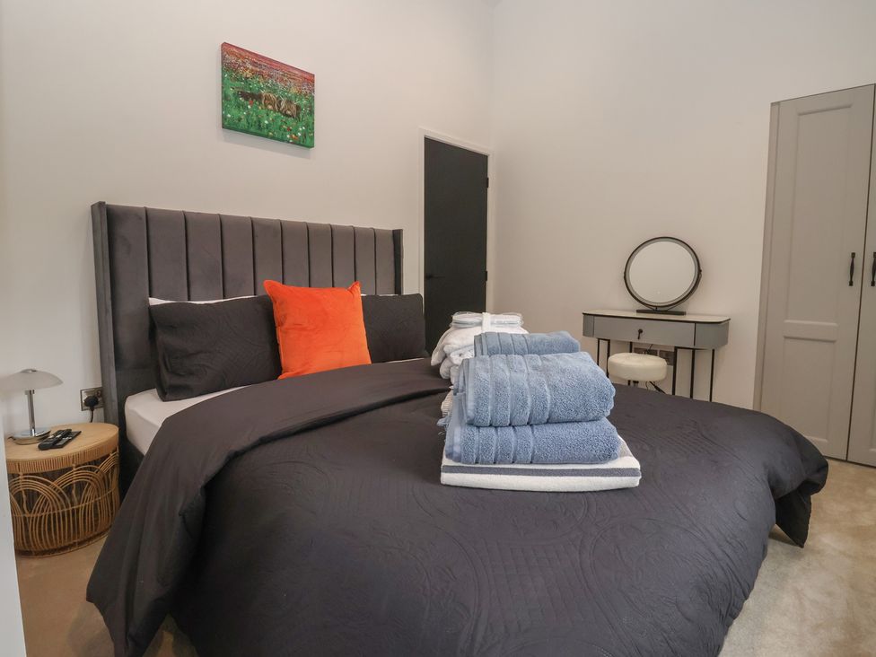 A bedroom featuring a bed with towels and a mirror at Wood Cottage Winterburn