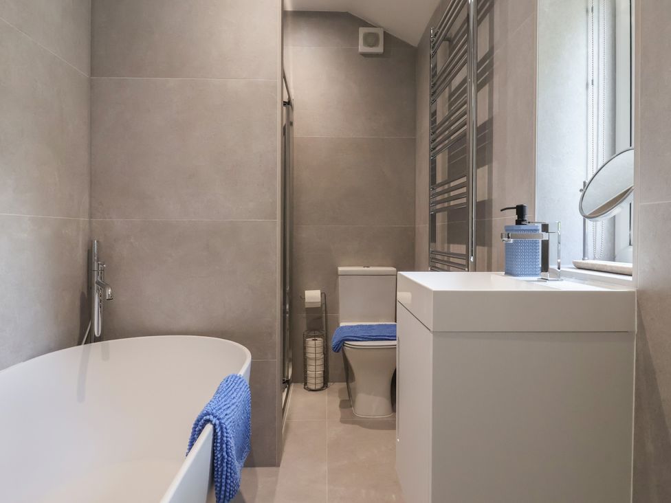 A bathroom featuring a bathtub, toilet, and sink at Wood Cottage in Winterburn