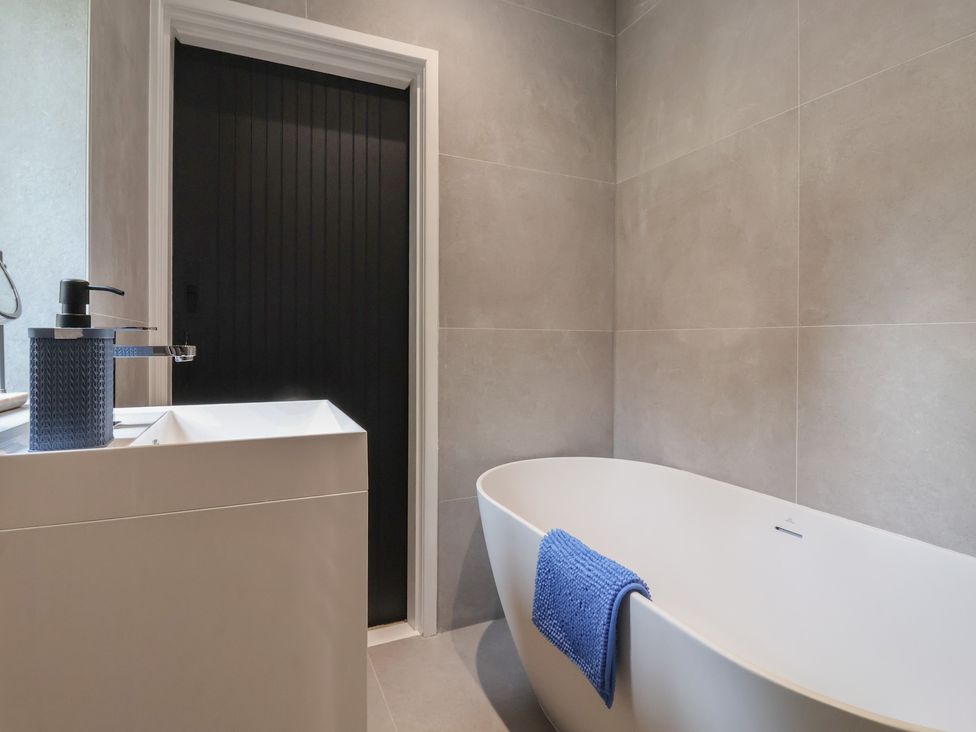 A bathroom with a bath tub and sink at Wood Cottage in Winterburn