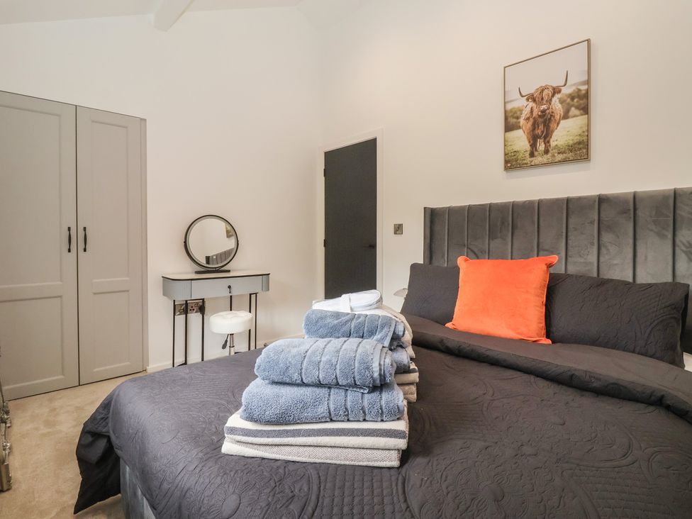 A bedroom with a bed and towels stacked at Wood Cottage in Winterburn