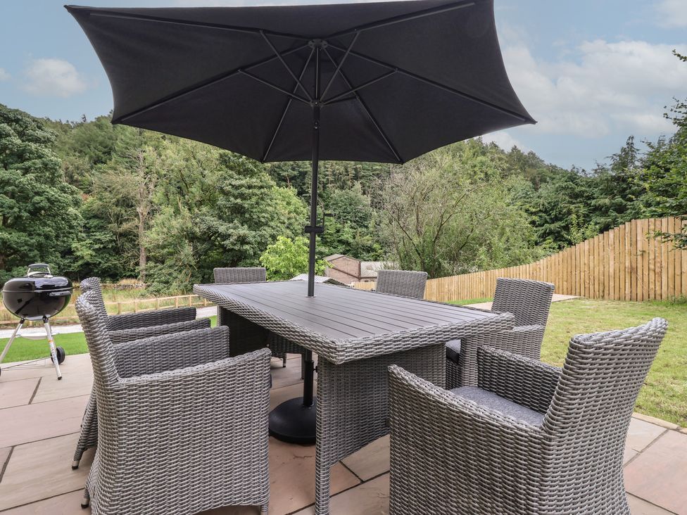 A patio with a table and chairs under an umbrella at Wood Cottage in Winterburn