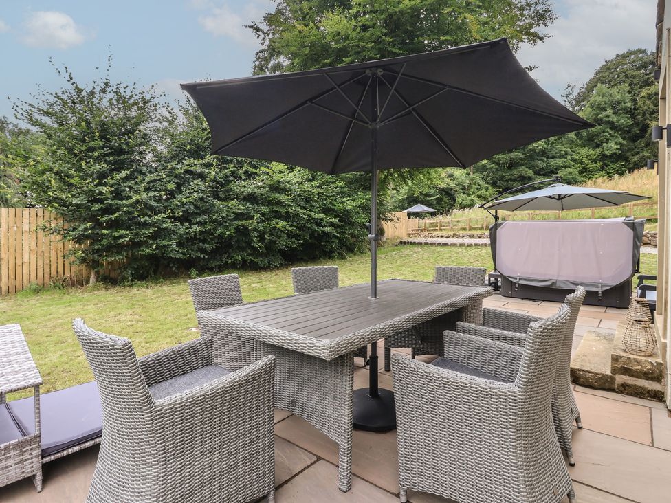 A garden with a table and chairs under an umbrella at Wood Cottage in Winterburn