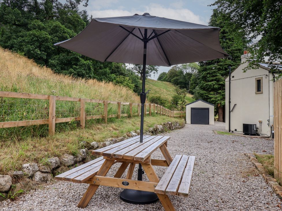 A picnic table with an umbrella in an outdoor area at Wood Cottage in Winterburn