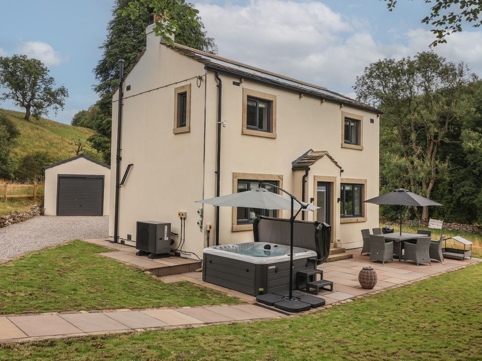 An outdoor area with a house, hot tub, and patio furniture at Wood Cottage in Winterburn