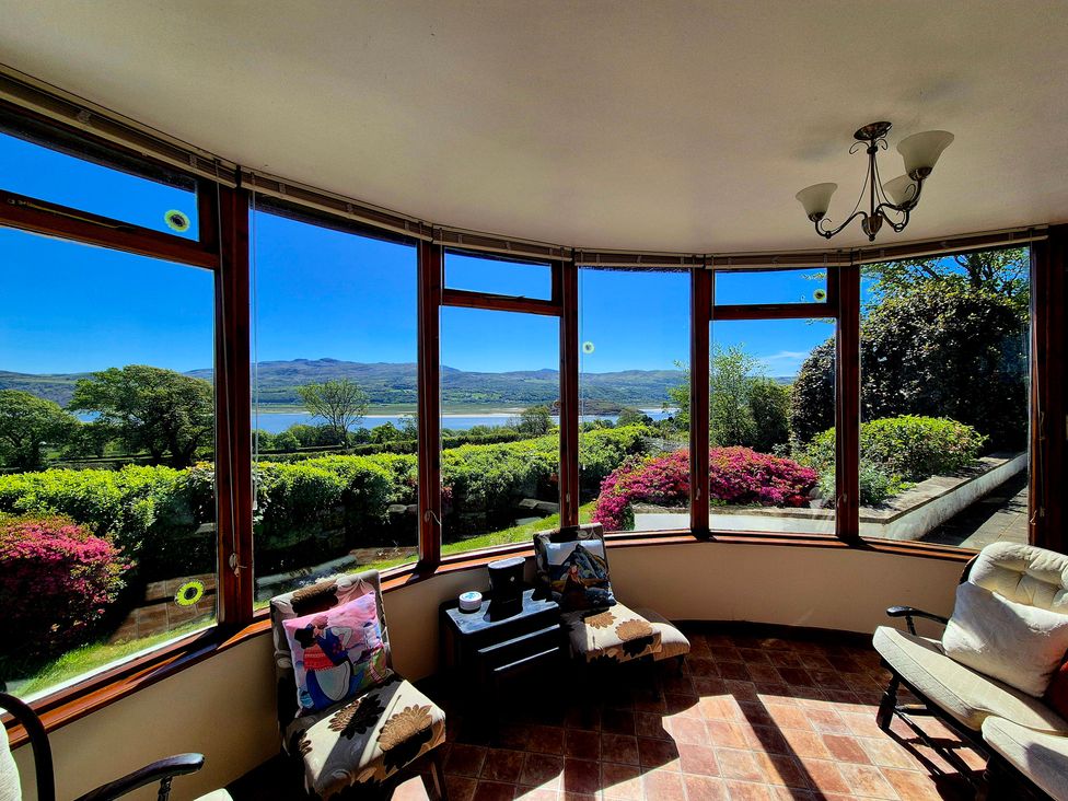 A conservatory with chairs and table overlooking a view at Artist's Cottage in Minffordd near Penrhyndeudraeth