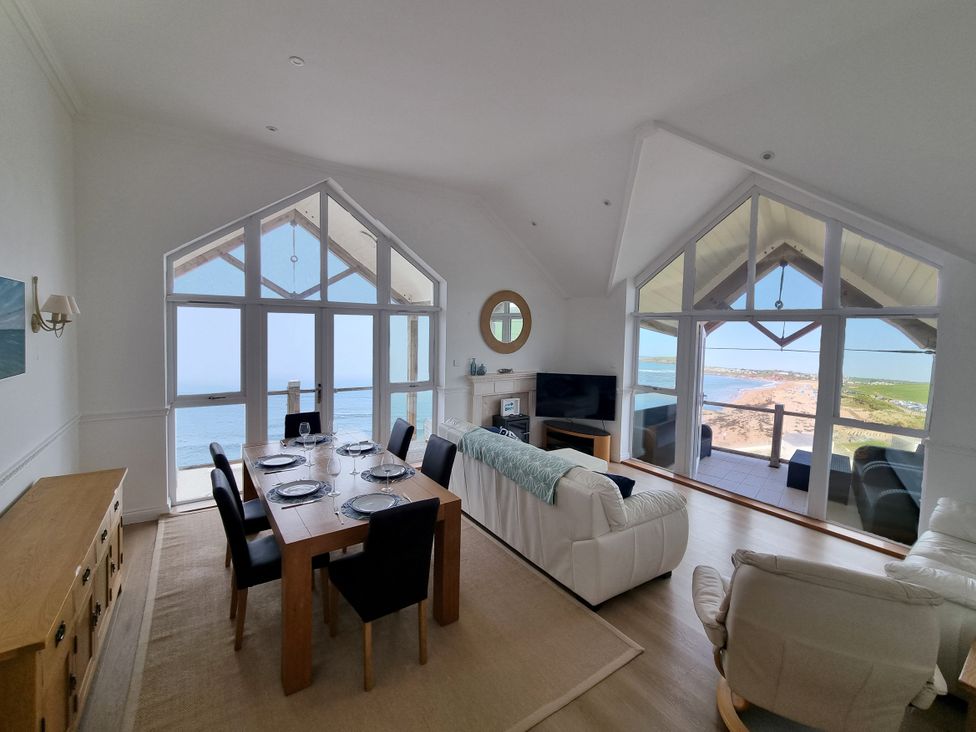 A living room with a dining table and sea view at Sea View Beach Apartment in Thurlestone