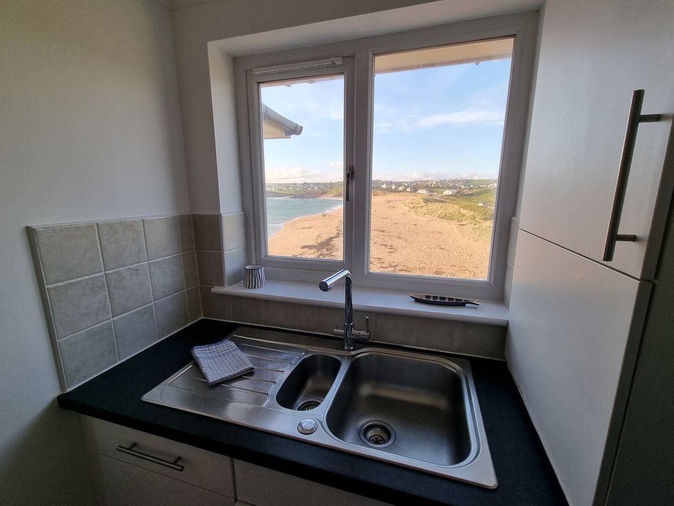 A kitchen with a sink and window overlooking the beach at Sea View Beach Apartment Thurlestone