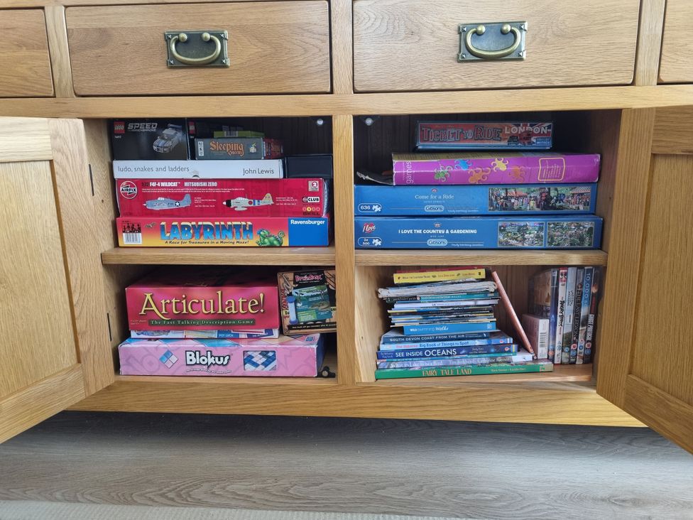 A cabinet with board games books and DVDs at Sea View Beach Apartment Thurlestone