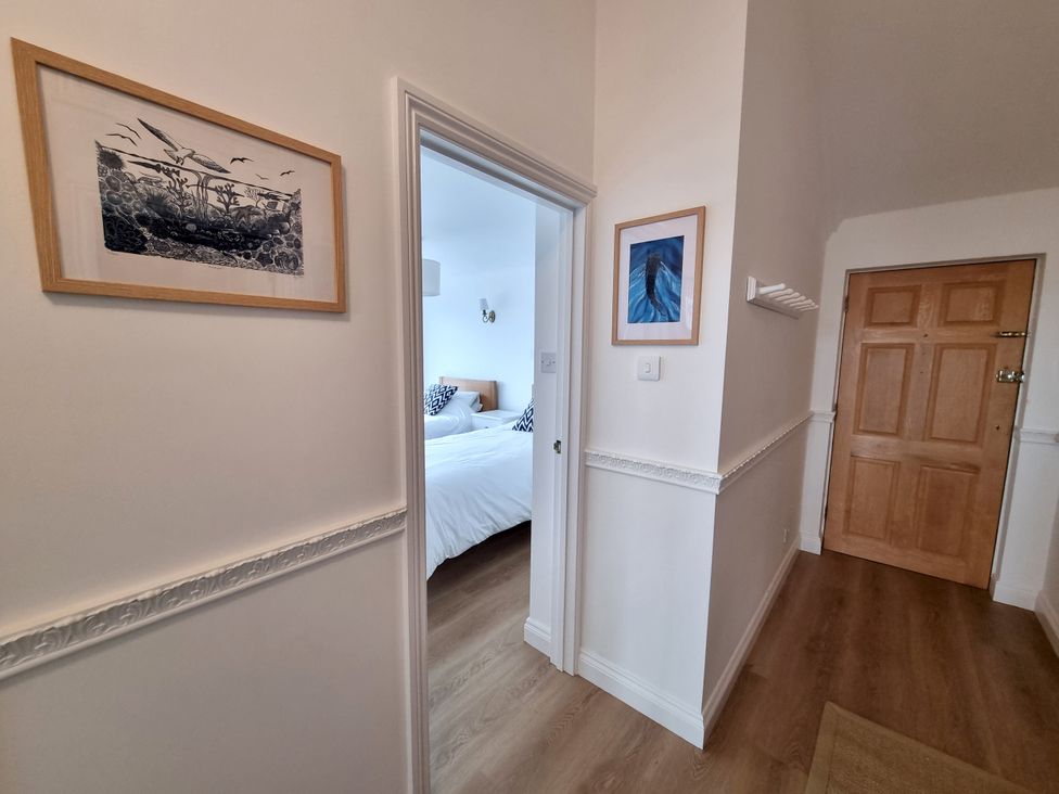A hallway with artwork and a door leading to a bedroom at Sea View Beach Apartment Thurlestone
