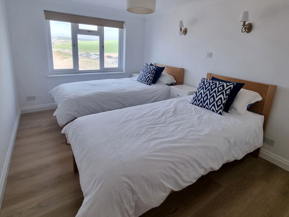 A bedroom with two beds and a window at Sea View Beach Apartment Thurlestone