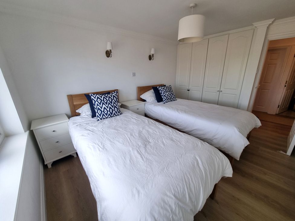 A bedroom with two beds and a wardrobe at Sea View Beach Apartment in Thurlestone