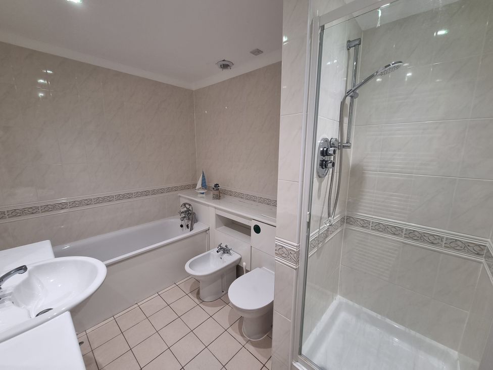 A bathroom with bathtub, shower, toilet, bidet and sink at Sea View Beach Apartment in Thurlestone