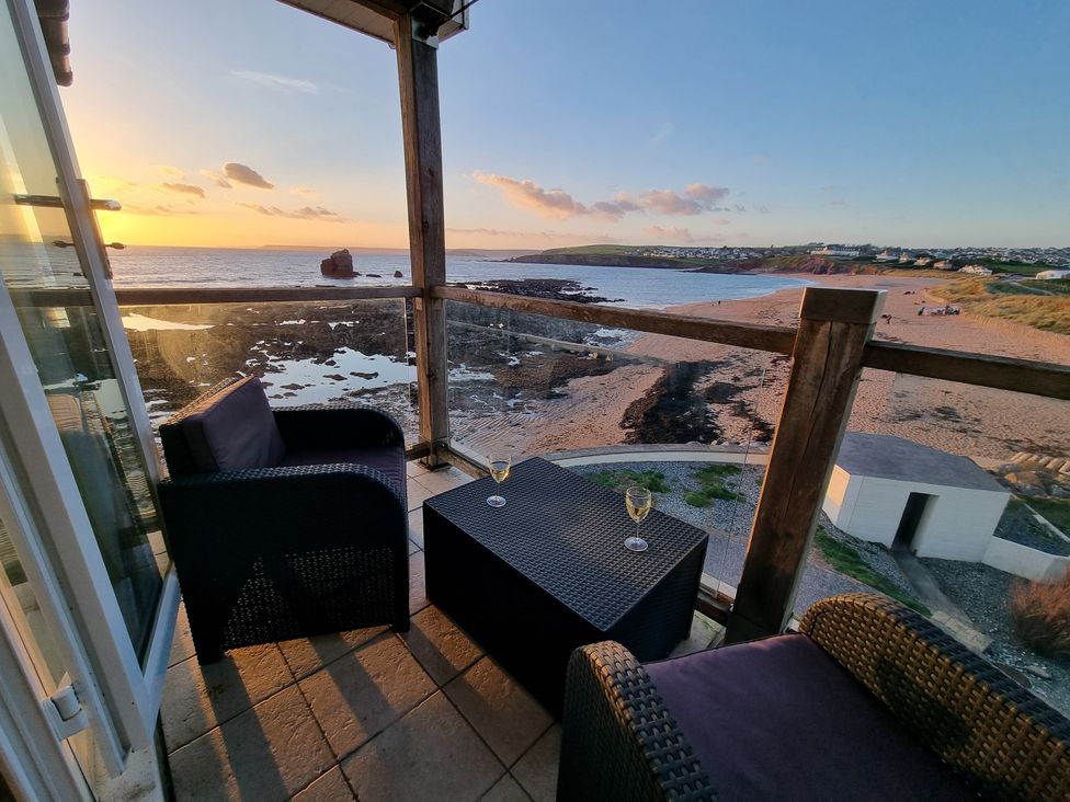 A balcony with chairs and a table overlooking the beach at Sea View Beach Apartment Thurlestone